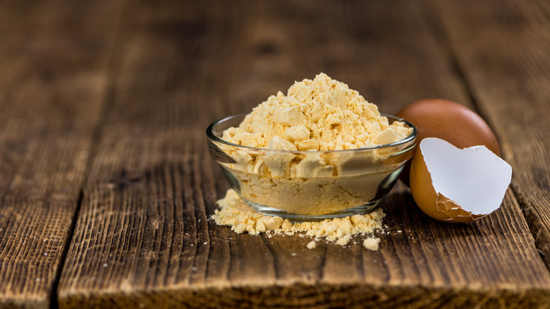 A bowl of egg powder next to egg shells