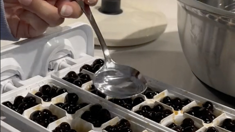 Hand spooning syrup onto trays of boba pearls