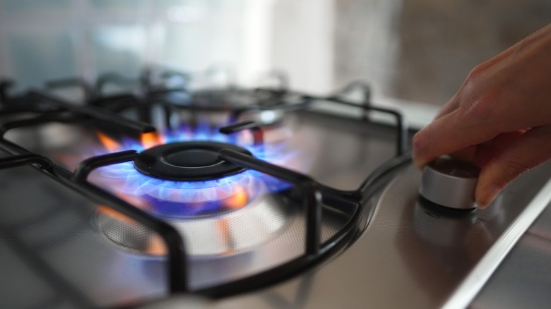 a hand turning on a gas stove