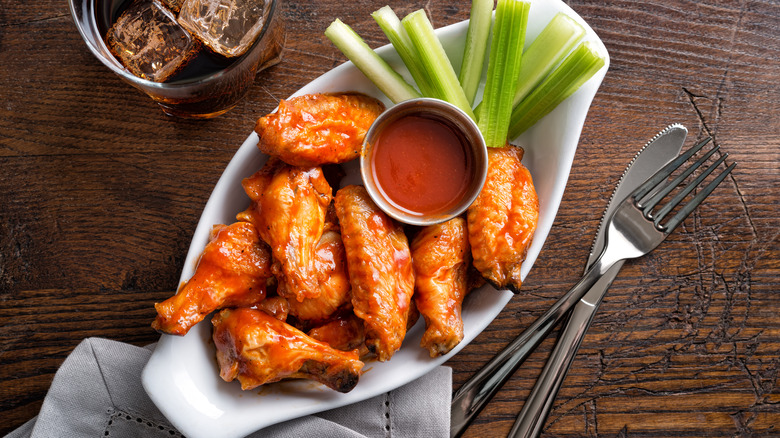 Plate of buffalo wings with sauce and celery