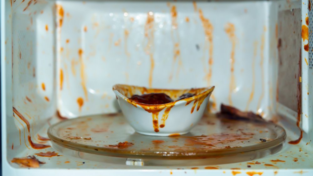 open microwave with exploded red sauce on the walls