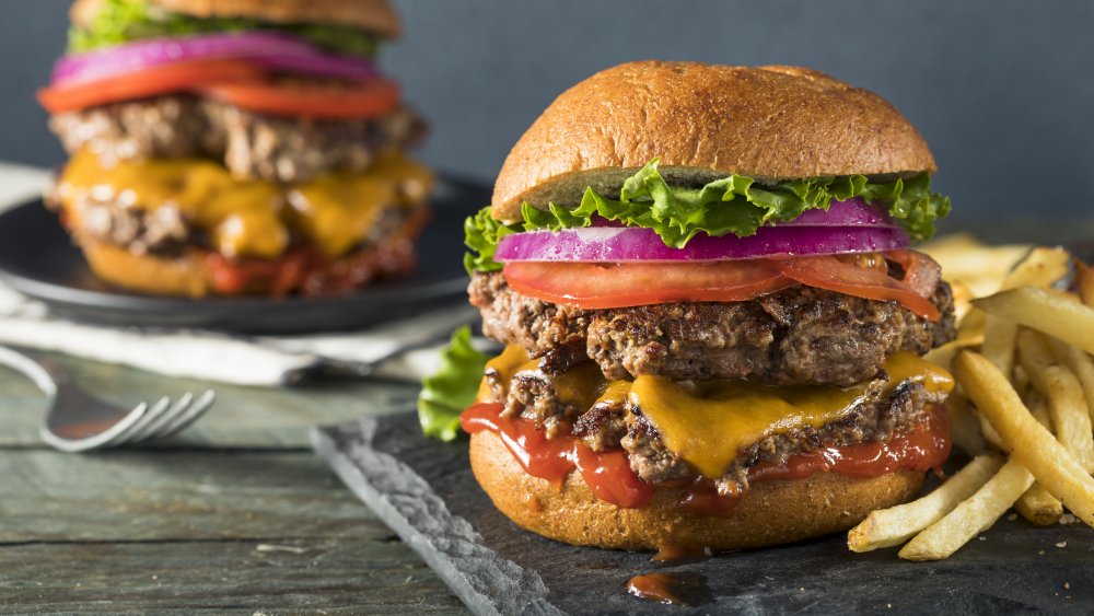 Smashed burgers with tomato, lettuce, red onion and fries.