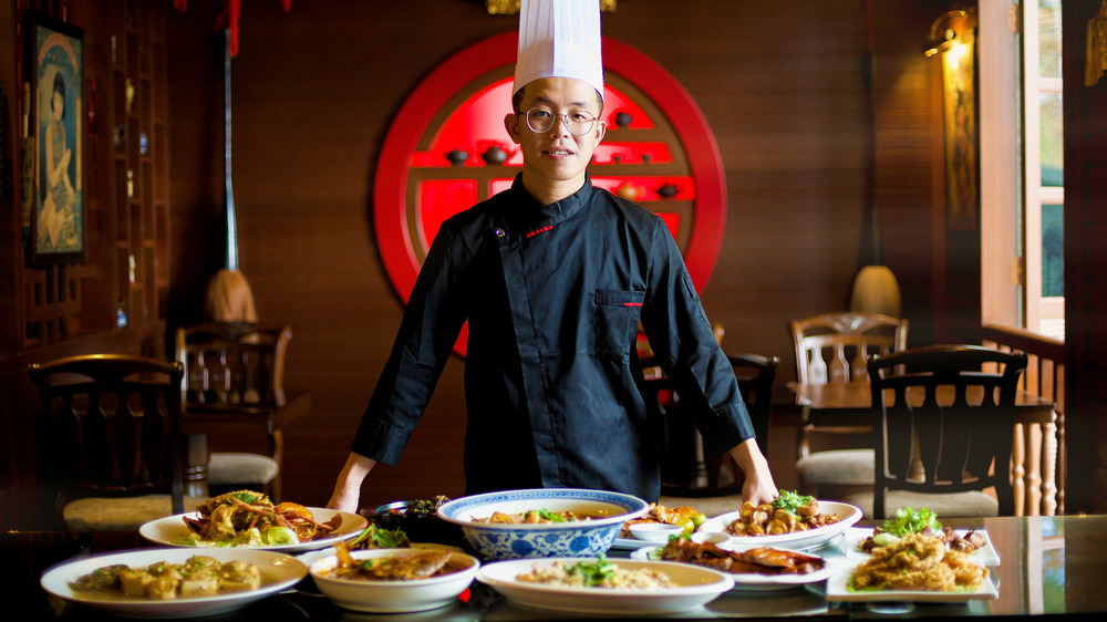 Asian chef standing in front of dishes