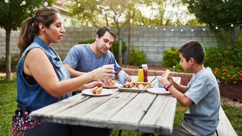 Family eating hot dogs outside