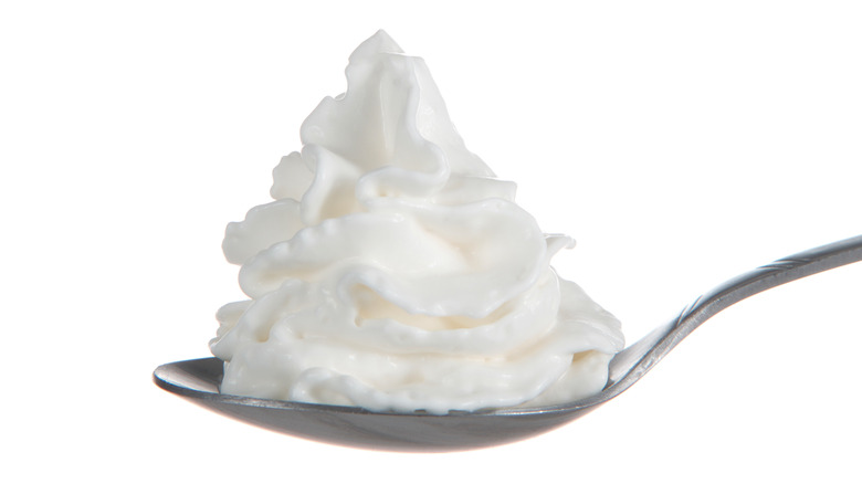 Spoon holding a mound of spray whipped cream.