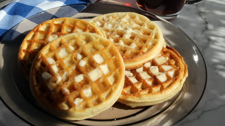 Four toasted frozen waffles on a plate with butter