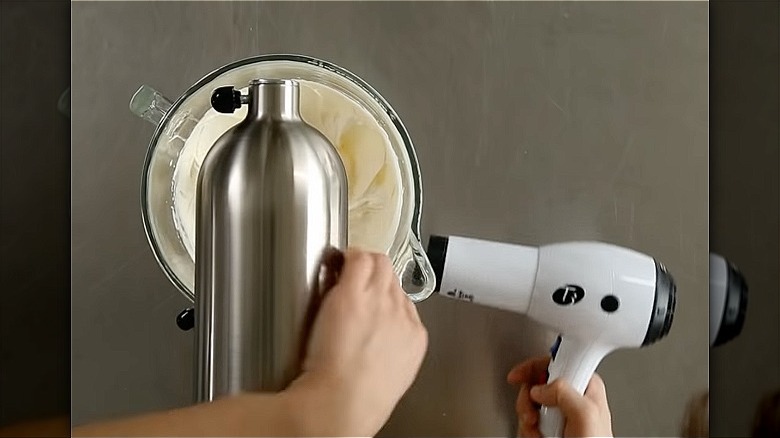 baker uses hairdryer on frosting