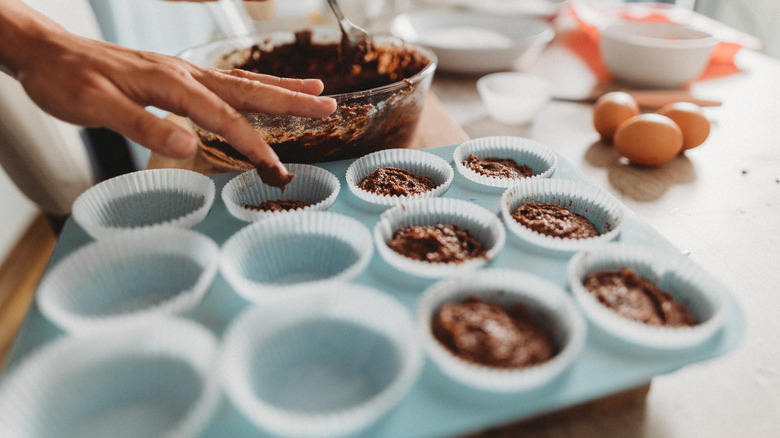 Person filling muffin tins with batter