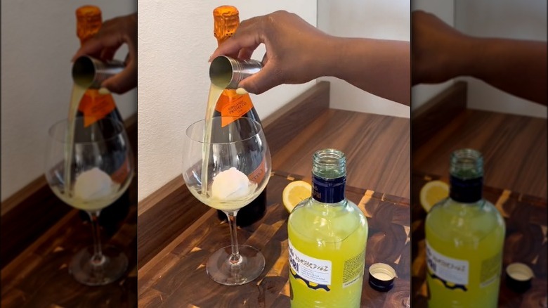 Person pouring limoncello over sorbet with bottle of prosecco in background