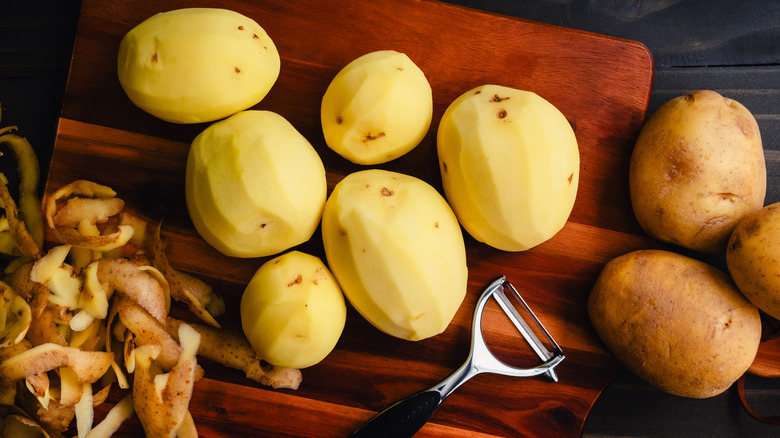 Whole, peeled Yukon Gold potatoes on wooden cutting board