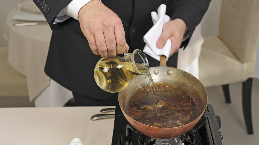 Person pouring wine into pan to deglaze