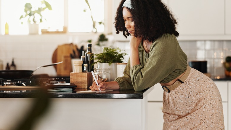 A person writing notes in the kitchen