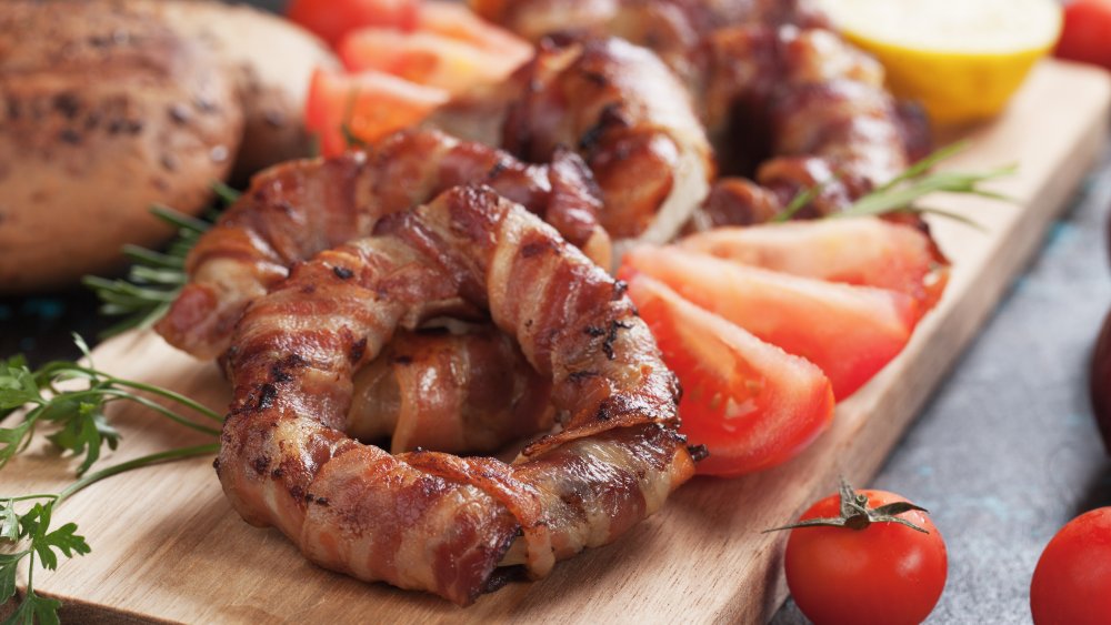 bacon-wrapped onion rings on a cutting board