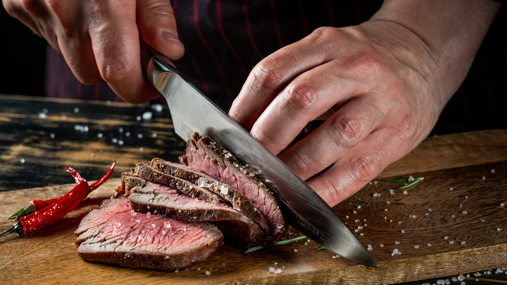 cutting seared steak for serving with large knife