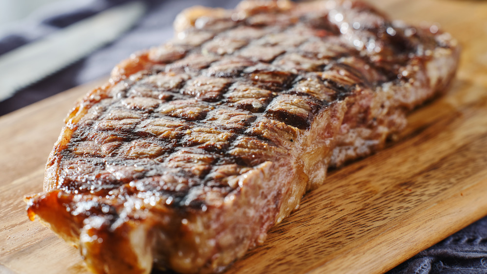 finished grill steak on wooden platter