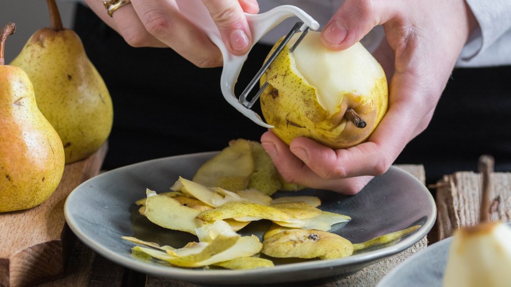 Hands peeling pears with a vegetable peeler