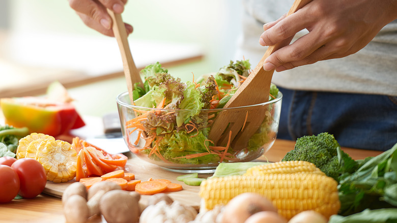 Person tossing a bowl of salad